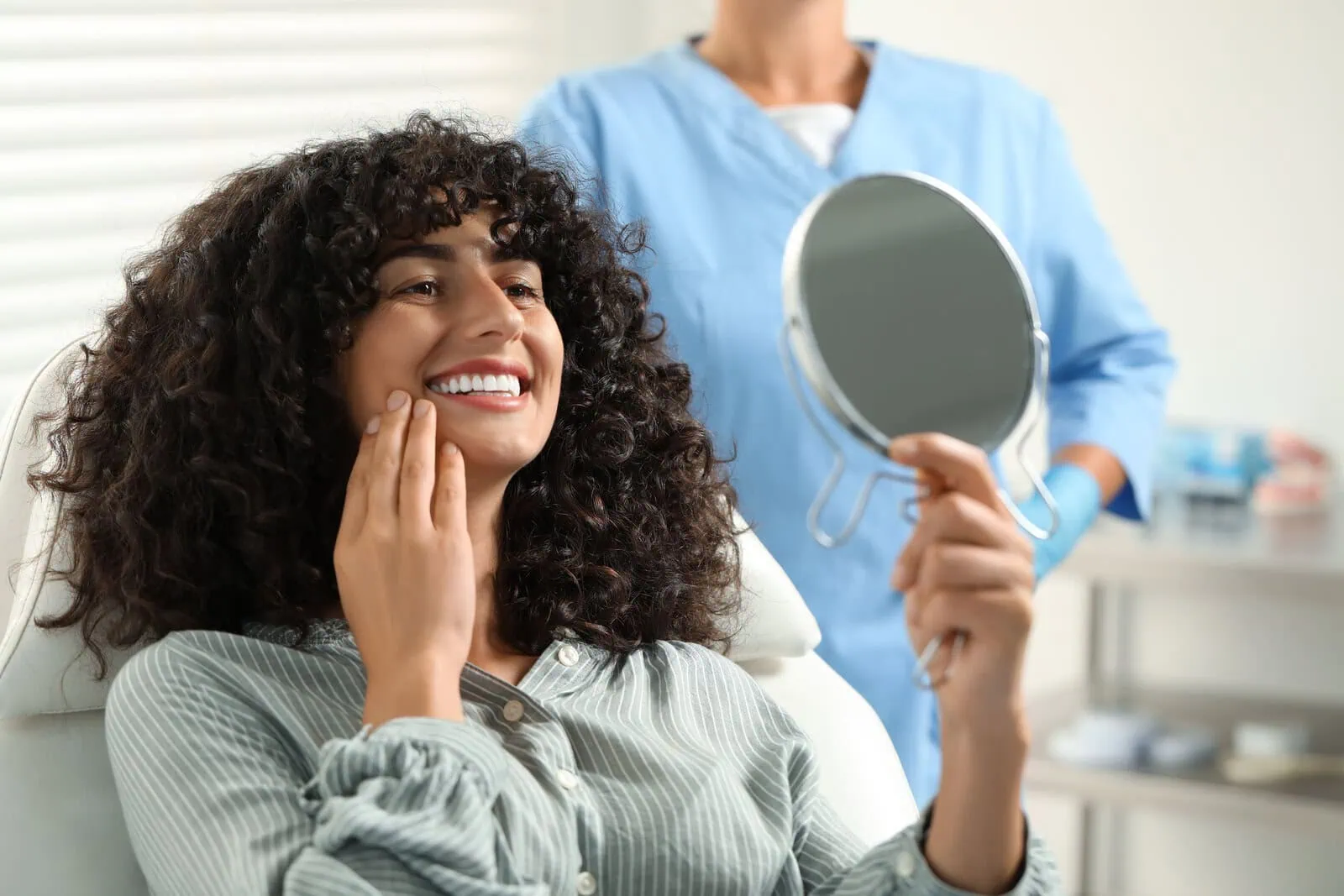 Patient checking her smile in a hand mirror after her visit